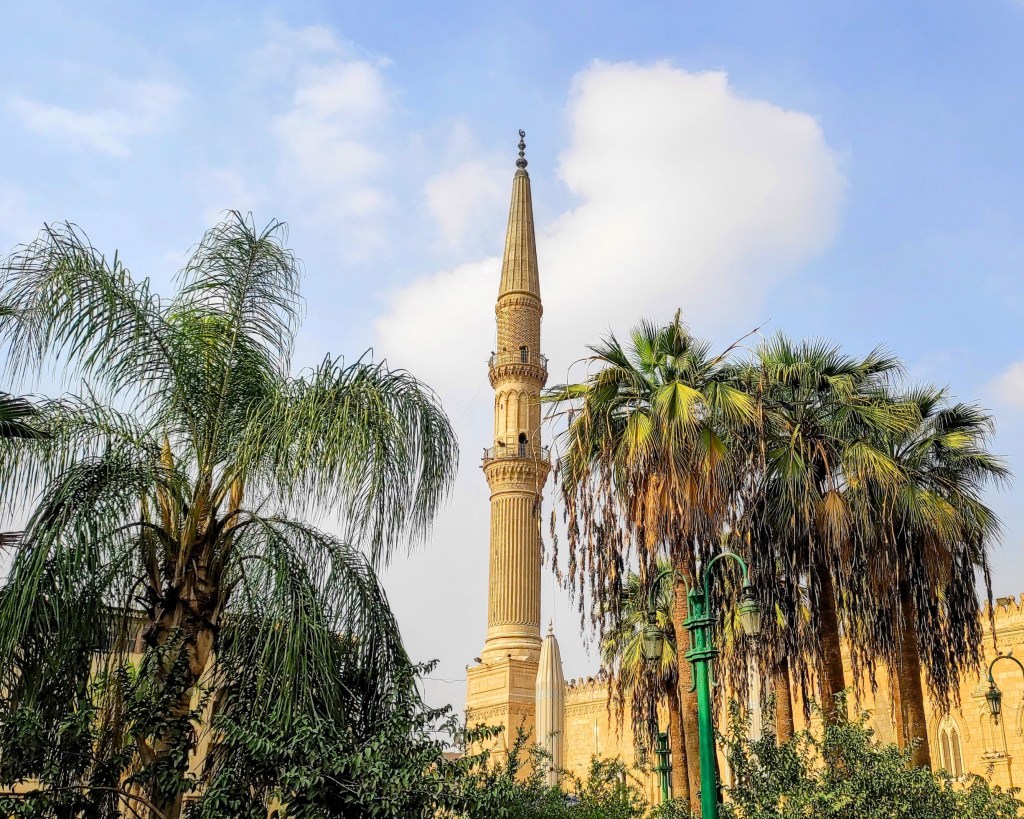 A minaret surrounded by palm trees 