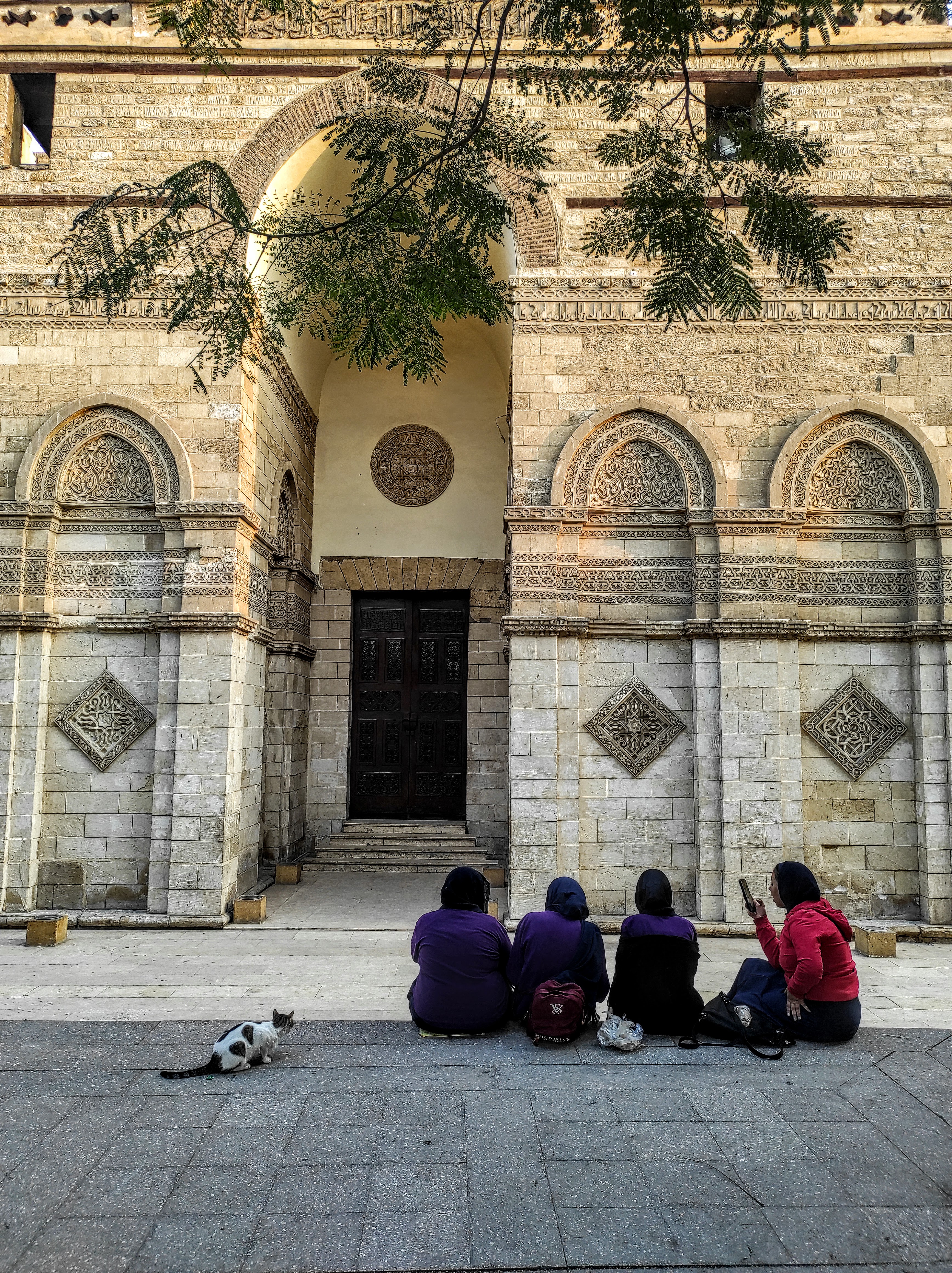 Women sitting in front of a carved stone building in Islamic Cairo